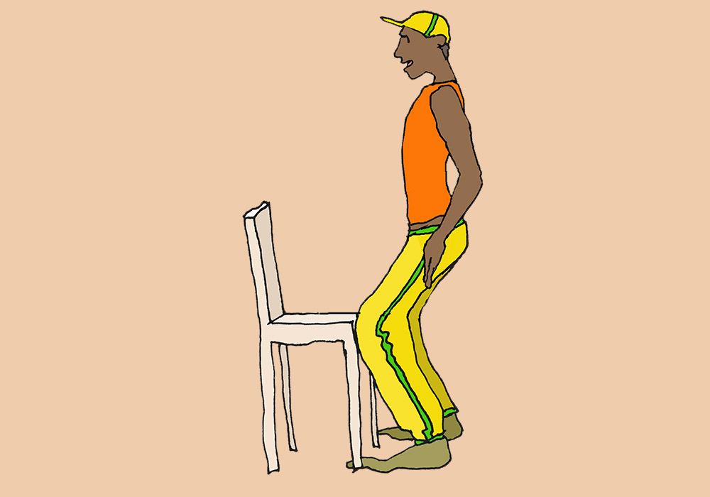 Ein Mann steht vor einem Stuhl mit leicht gebeugten Knien und schaukelt sein Becken nach hinten
